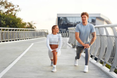 Téléchargez les photos : Un couple en tenue de sport se réchauffe avant de courir dehors. Exercices matinaux et jogging. Sports et loisirs, mode de vie actif. - en image libre de droit