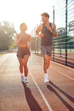 Photo for Couple in sportswear running at the stadium. Morning exercises and jogging. Sports and Olympic Games, active lifestyle. - Royalty Free Image