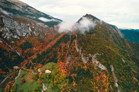 Téléchargez les photos : Une vue aérienne à couper le souffle d'une montagne boisée entourée de nuages, mettant en valeur la beauté naturelle du paysage avec sa végétation luxuriante et ses pentes ondulantes - en image libre de droit