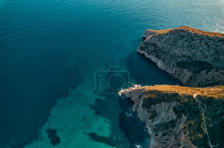 Photo for A breathtaking aerial view of a rugged headland with azure waters crashing against the cliffs, showcasing the beauty of coastal landforms and natural landscapes - Royalty Free Image