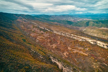 Téléchargez les photos : Vue aérienne panoramique d'une vallée entourée de montagnes sous un vaste ciel avec des nuages épars. Le paysage présente diverses communautés végétales, prairies et terrains accidentés - en image libre de droit