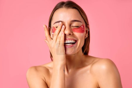 Photo for Beautiful woman with moisturizing patches under her eyes isolated on pink background. Facial skin care, cosmetology, beauty concept. - Royalty Free Image