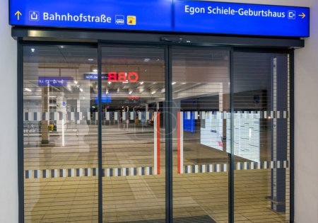 Foto de Glass sliding door with blue info signs at the exit to the famous painter Egon Schiele birthplace from the trainstation of Tulln at the Danube, Austria - Imagen libre de derechos