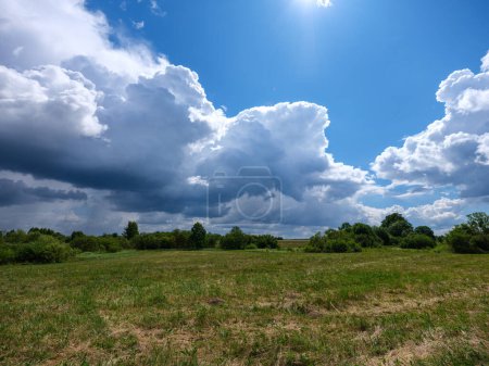 Photo for White rain clouds over countryside in summer with blue sky and high contrast - Royalty Free Image