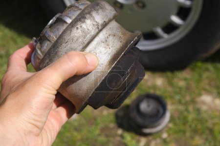 Foto de Hand with used rubber engine mounts. Changing rubber car pads used for engine and shock absorption. - Imagen libre de derechos