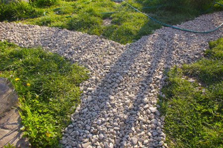 Photo for Intersection of decorative gravel paths in a rustic grass yard. Pretty paths in the garden in the rays of the sunset. - Royalty Free Image