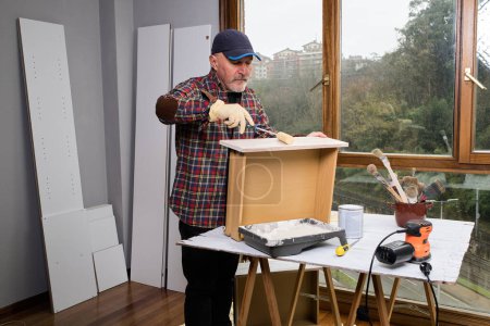 Foto de Hombre maduro pintando un mueble viejo para darle una nueva vida - Imagen libre de derechos