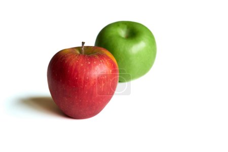 Une pomme rouge et une pomme verte vibrante sont centrées sur un fond blanc uni, éclairé par la lumière naturelle. La surface des pommes est lisse avec un éclat légèrement brillant.