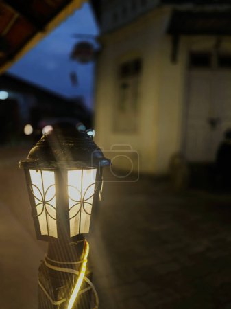 In den ruhigen Straßen von Ooty steht ein einsamer Laternenpfahl, dessen sanftes Glühen ein warmes und einladendes Licht auf das Kopfsteinpflaster darunter wirft. Vor dem Hintergrund der ruhigen Nacht wird der Laternenpfahl zum Leuchtfeuer des Komforts und der Sicherheit.