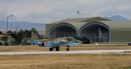 Foto de Konya Turkey JUNIO, 29, 2022 Avión militar en camuflaje marrón con hangares y fondo de cielo gris. Copiar espacio. Sukhoi Su-25 Frogfoot de la Fuerza Aérea de Azerbaiyán - Imagen libre de derechos
