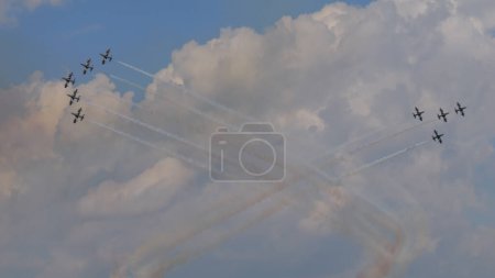 Téléchargez les photos : Ghedi Italie 8 SEPTEMBRE 2022 Deux formations d'avions militaires dessinent une croix dans le ciel bleu avec des bombes fumigènes blanches se croisant lors d'une démonstration de voltige aérienne. Italien Frecce Tricolori - en image libre de droit