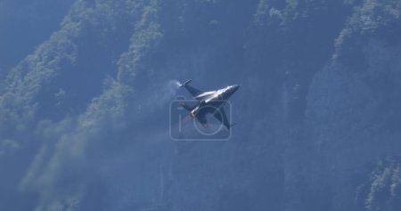 Foto de Mollis Suiza 19 de agosto de 2023: Aviones de combate se elevan a alta velocidad a baja altitud sobre el bosque verde. Copiar espacio. General Dynamics F-16 Fighting Falcon of Belgian Air Force Viper Demo - Imagen libre de derechos