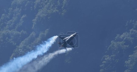 Téléchargez les photos : Mollis Suisse 19 août 2023 : Avion de combat volant à haute vitesse à basse altitude au-dessus de la forêt verte. Espace de copie. Général Dynamics F-16 Faucon combattant de l'armée de l'air belge Viper Demo - en image libre de droit