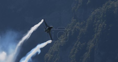 Photo for Mollis Switzerland August 19 2023: Combat Aircraft Soaring at High-Speed Low Altitude Over Green Forest. Copy Space. General Dynamics F-16 Fighting Falcon of Belgian Air Force Viper Demo - Royalty Free Image