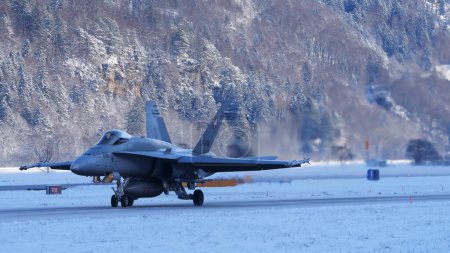 Photo for Meiringen Switzerland January 19 2023: Fighter jet taxiing in white winter snow scenario. Copy Space. Boeing F-18 Hornet of Swiss Air Force air defense for World Economic Forum WEF in Davos. - Royalty Free Image