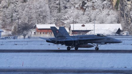 Photo for Switzerland January 19 2023: F-18 Hornet of Swiss Air Force taxiing on runway in enchanting snowy landscape of Meiringen airport ready for winter mission during the World Economic Forum WEF in Davos - Royalty Free Image