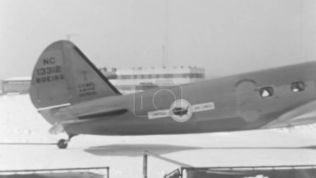 Photo for Evocative black and white image of a 1930s propeller airliner. The photo shows the tail and passenger door, with the aircraft parked on a snowy airport. Boeing 247 of United Air Lines - Royalty Free Image