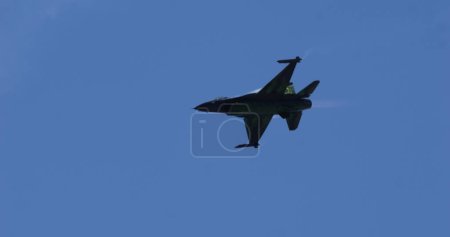 Téléchargez les photos : Mollis Suisse 19 août 2023 : Stark silhouette noire d'un chasseur F-16 dans le ciel. Espace de copie pour les nouvelles et le contenu thématique militaire. F-16 Lutte contre le faucon de l'armée de l'air belge. - en image libre de droit