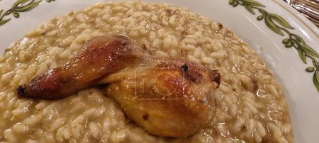 Close-up of a succulent baked quail leg served on a bed of creamy risotto