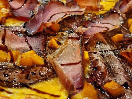 Close-up of tender roasted pork slices atop baked squash, drizzled with a rich balsamic glaze