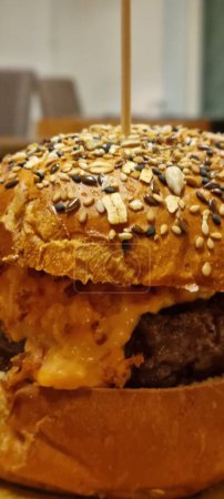 Close-up of a juicy cheeseburger with various seeds on the bun