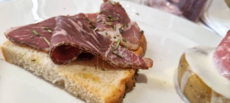 Close-up of a delicious prosciutto sandwich garnished with herbs, served on crusty bread