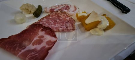 Italian antipasto plate with sliced cold meats, pickles, and polenta
