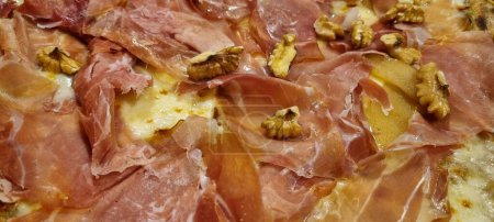 Imagen de alta resolución que muestra los ingredientes de una sabrosa pizza de jamón y nuez