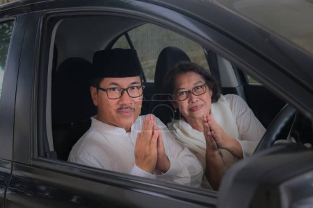 Photo for Adult moslem husband and wife greeting from inside the car cabin - Royalty Free Image