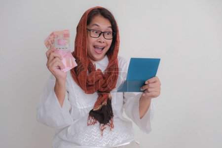 Téléchargez les photos : Asiatique femme tenant son livret de banque et un peu d'argent dans ses mains - en image libre de droit