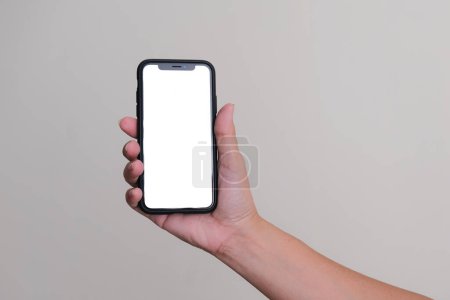 Téléchargez les photos : Main tenant un smartphone sur fond plat blanc - en image libre de droit