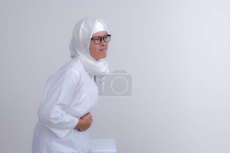 Téléchargez les photos : Faim fille musulmane pressant son estomac en attendant le temps de pause de jeûne, pendant le mois de ramadan - en image libre de droit