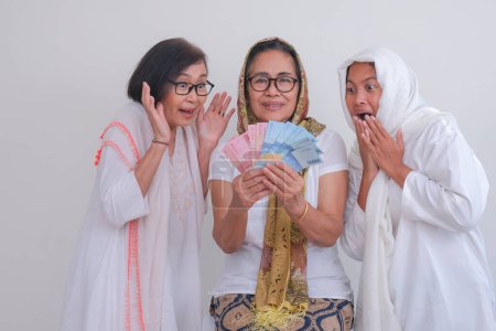 Foto de Dos hijas que parecen emocionadas por recibir algo de dinero para el regalo de Ramadán de su madre - Imagen libre de derechos
