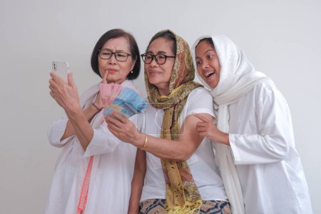 Foto de Tres mujeres tomando fotos de selfies juntas, sosteniendo algo de dinero en la mano - Imagen libre de derechos