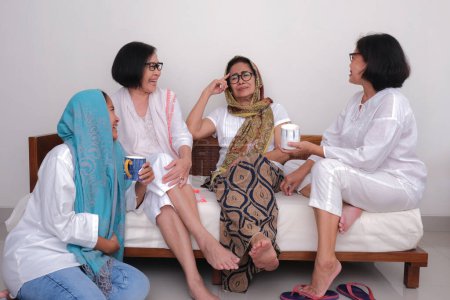 Foto de Tres mujeres sentadas con su madre que les está contando historias divertidas - Imagen libre de derechos