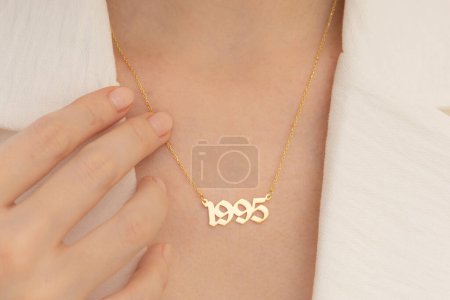 Portrait of elegant woman wearing jewelry: personalized silver necklace. Woman in white outfit with soft color make-up.