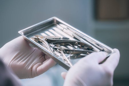 Photo for A girl in gloves holds a tray with sterile medical instruments for pedicure. - Royalty Free Image
