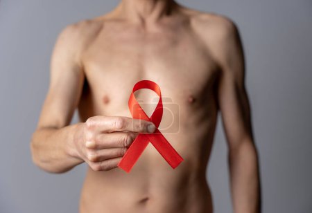 Foto de Still life. Studio shot of a folded red ribbon held by a shirtless man - Imagen libre de derechos