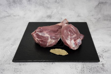 Photo for French culinary Still Life. Piece of Lamb shank placed on a black tile top. - Royalty Free Image