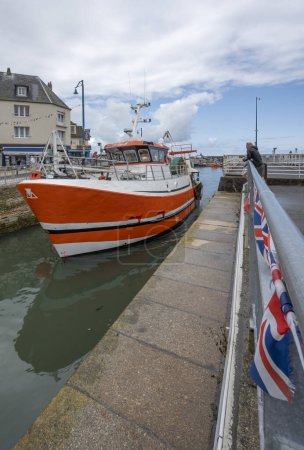 Foto de Port-en-Bessin-Huppain, Francia - 07 24 2023: Un barco pesquero naranja entra en el puerto - Imagen libre de derechos
