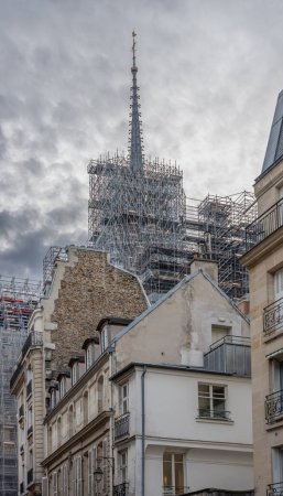 Paris, France - 02 15 2024: Notre Dame de Paris. View of the spire topped with the golden rooster of Notre-Dame cathedral emerging from the immense scaffolding of metal tubes
