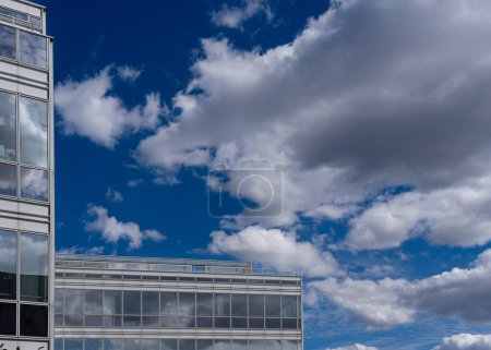 Eco-barrio. Vista de un cielo azul con nubes blancas y parte de un edificio azul