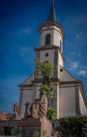 Blick auf die Kirche Saint-Louis in Duttlenheim und ein Storchennest auf dem Dach