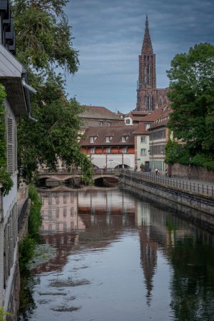Strasbourg, France - 06 28 2023 : Ville de Strasbourg : Vue des façades alsaciennes typiques et de la cathédrale Notre-Dame de Strasbourg depuis les ponts couverts de Strasbourg le long de l'Ill