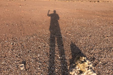 Foto de Silueta del hombre en la arena en la playa durante la puesta del sol. sombra del hombre en la arena de la playa. - Imagen libre de derechos