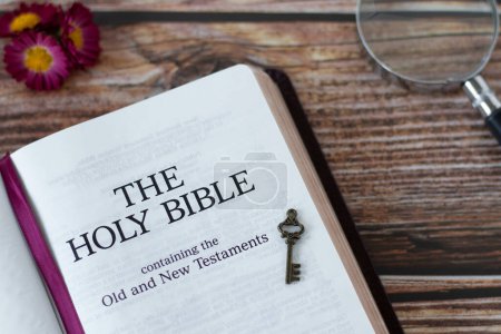 Photo for Holy Bible Book with ancient key and magnifying glass on wooden background. Top view. Christian study of old and new testament Scripture, wisdom, prophecy, and revelation from God Jesus Christ. - Royalty Free Image