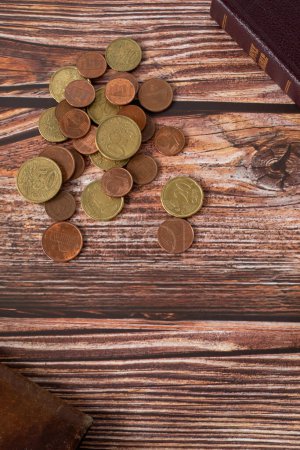 Photo for Coins on wooden background with holy bible book and wallet. Vertical shot, copy space, top view. Christian biblical concept of tithing, religious offering, giving thanks to God Jesus Christ. - Royalty Free Image