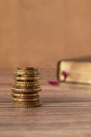 Photo for Stack of coins and holy bible book with golden pages on a wooden background. Copy space for text. A closeup. Christian tithing, giving, and religious offering concept. - Royalty Free Image