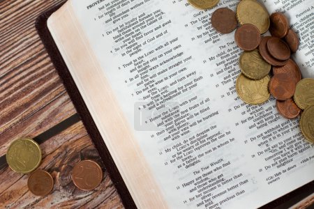 Photo for Coin money on open Holy Bible. Concept of Christian tithing, religious offering, and contribution to church of God Jesus Christ. Old Testament proverbs book. - Royalty Free Image