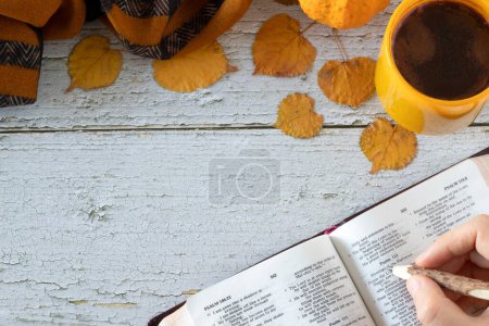 Téléchargez les photos : Crayon à main sur un livre de bible saint ouvert avec une tasse de café et des feuilles d'automne sur une table en bois. Vue du dessus, espace de copie. Étudier et lire les Écritures, concept biblique chrétien. - en image libre de droit